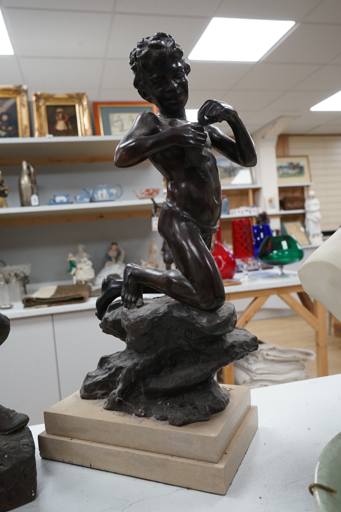 A bronze figure of a young boy carrying dead game, signed August, and a classic bronze of a young boy holding a fish, indistinctly signed, largest 53cm high